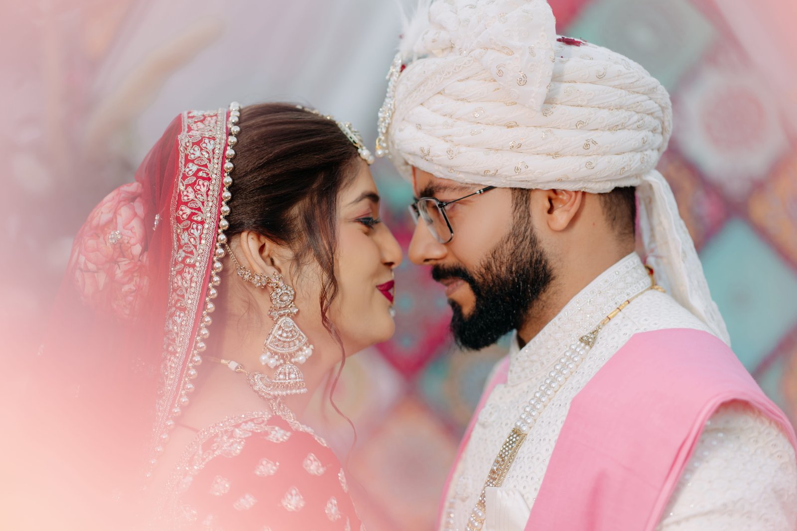 Bride and groom forehead to forehead in soft pastel light on their wedding day